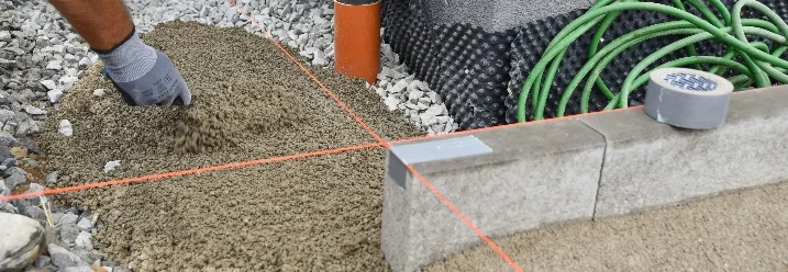 Person verteilt Kies mit der Hand