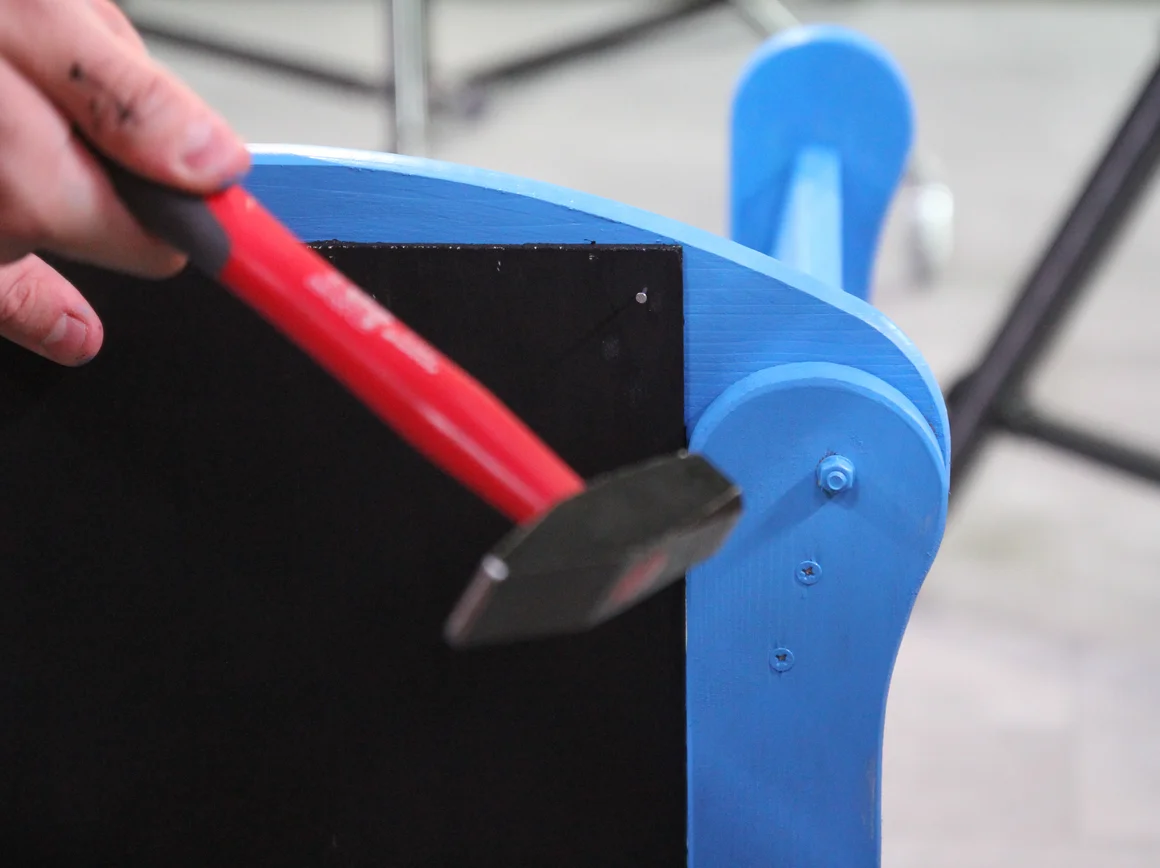 Person hämmert auf blaues Möbelstück