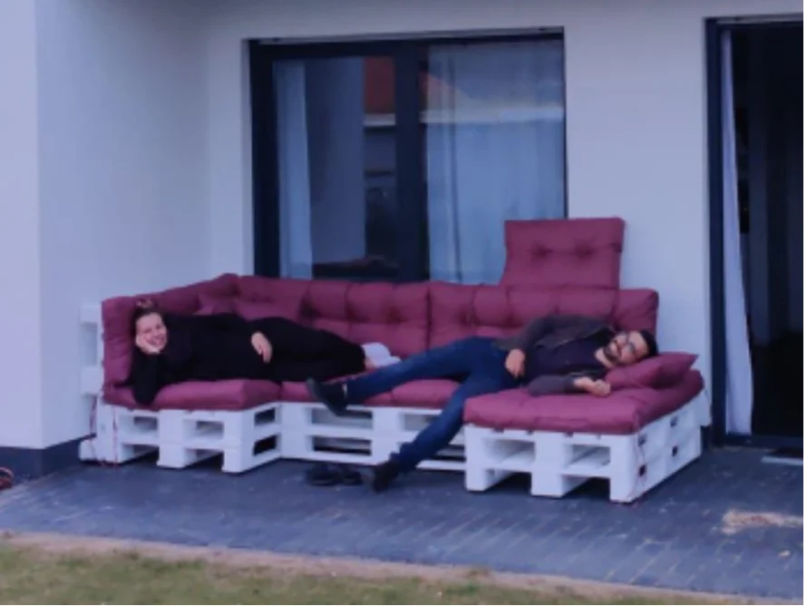 Zwei Personen entspannen auf einer selbstgebauten Palettensofa