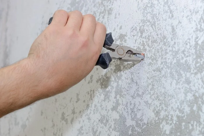 Hand entfernt Dübel mit Zange