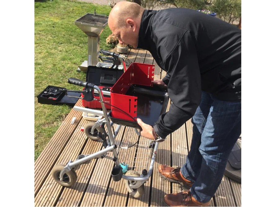 Person baut einen Grill auf einer Holzterrasse zusammen