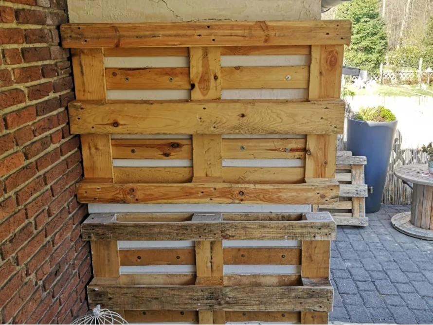 Holzpaletten an einer Backsteinmauer.