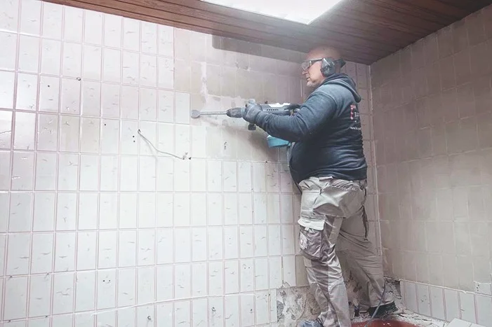 Person entfernt Fliesen mit Bohrhammer