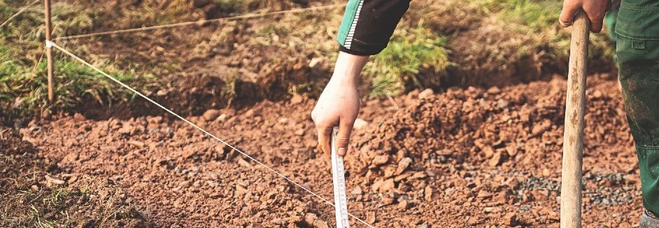 Person misst Baugrube mit Zollstock aus