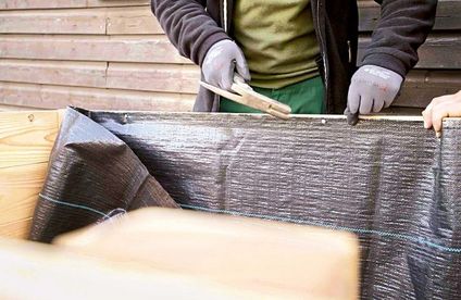 Hochbeet bauen – Anleitung Ein Maschendrahtgewebe wird an den Kanten des Hochbeets befestigt.