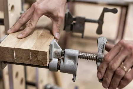 Zwei Holzteile werden mit Schraubzwingen fixiert.