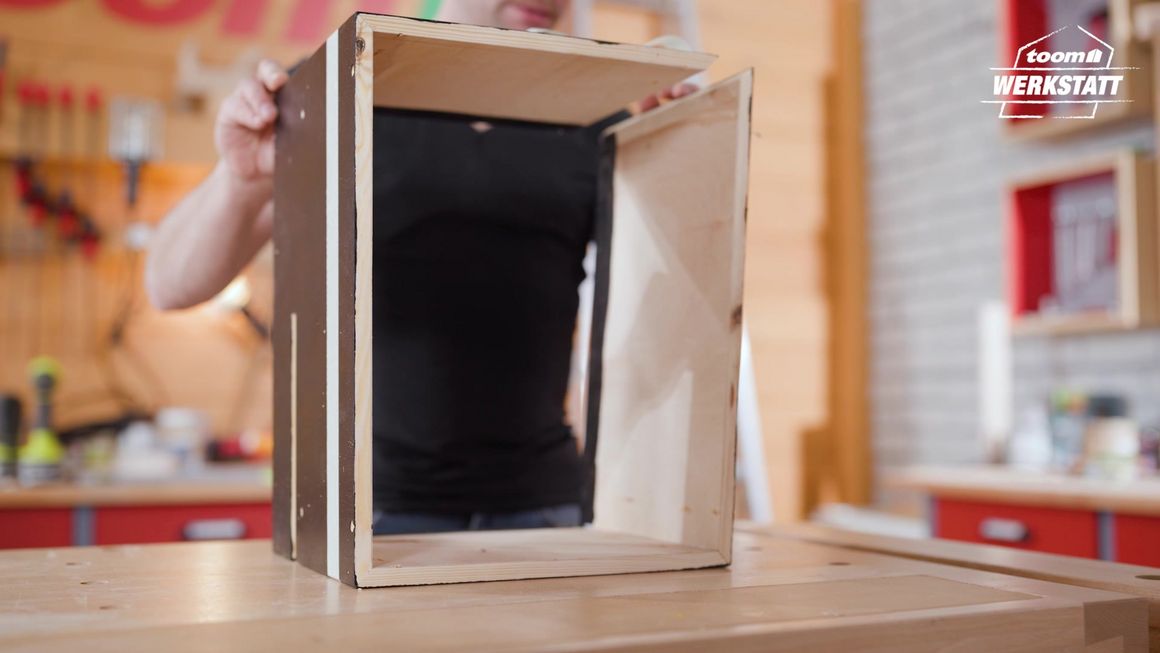 Person baut Holzkasten zusammen