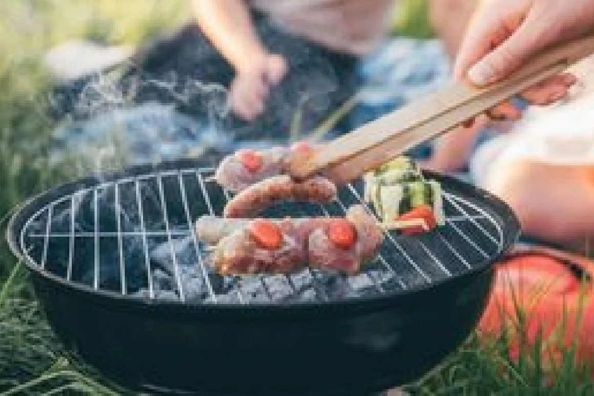 Person grillt Fleisch und Gemüse