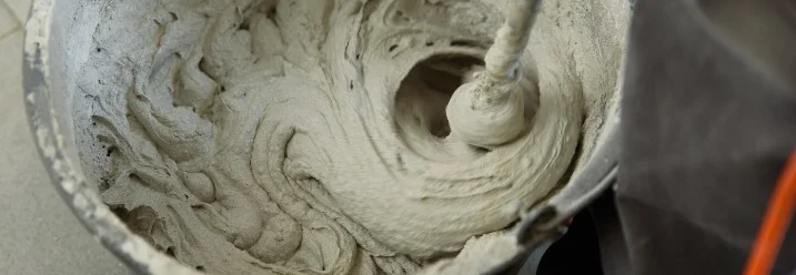 Mörtel wird in einem Eimer mit einem Rührgerät verrührt