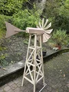 Eine selbstgebaute, unfertige Windmühle aus Holz steht im Freien auf einer Terrasse.
