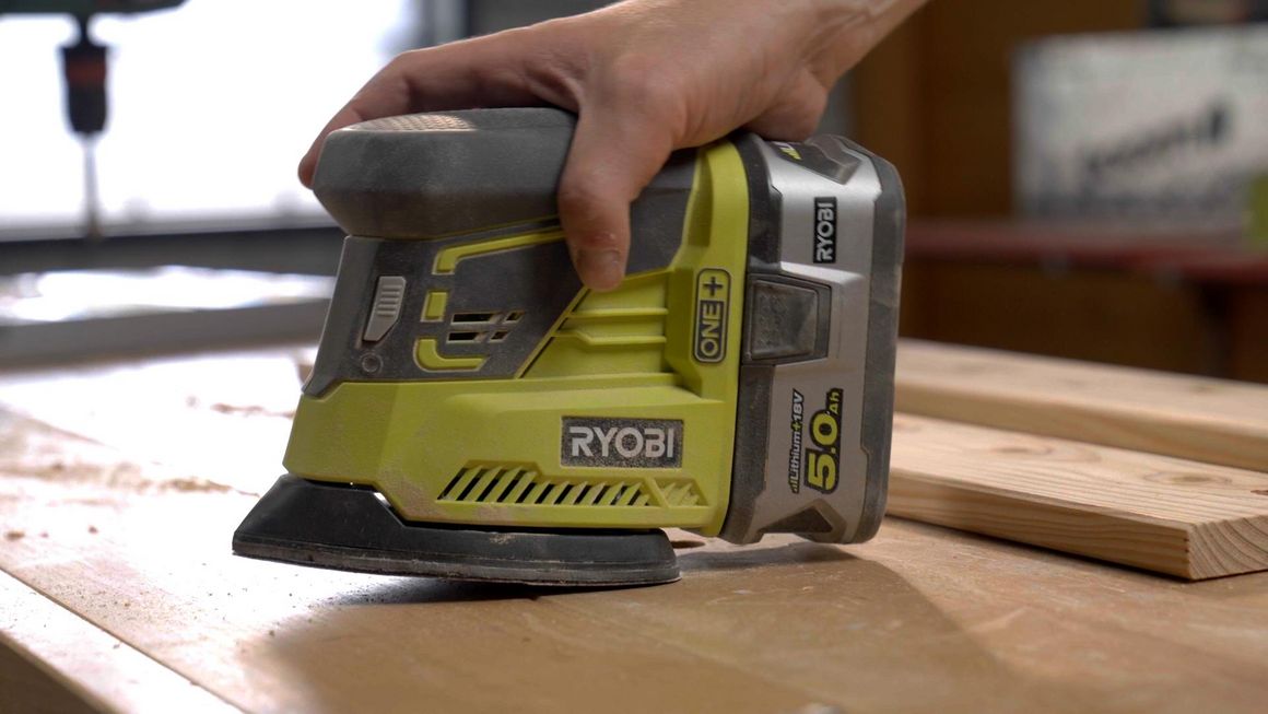 Person schleift Holz mit einem Schwingschleifer