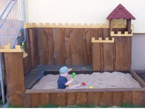 Kleinkind in einem Sandkasten aus Holz