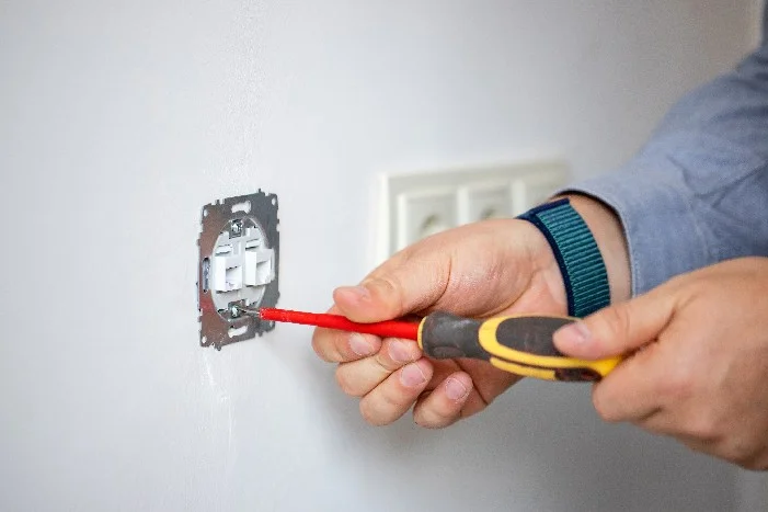 Person montiert Steckdose mit Schraubendreher.