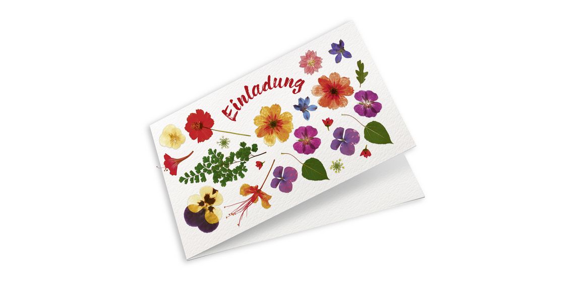 Eine Einladungskarte mit gepressten Blumen.