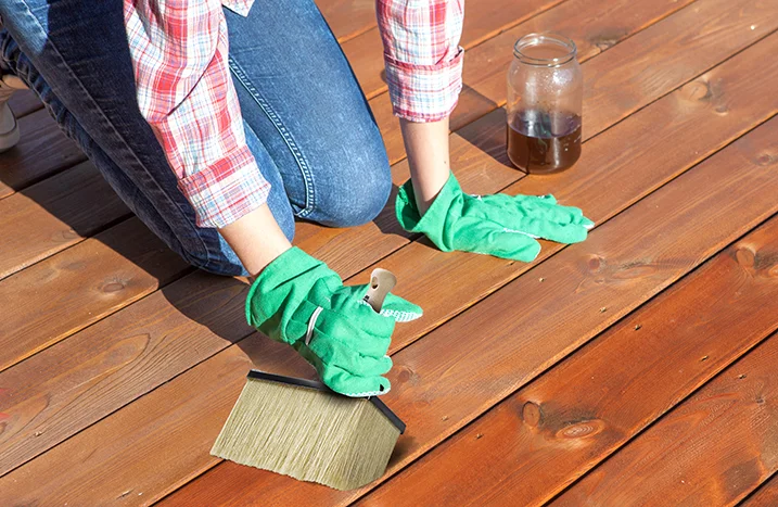 Person ölt Holzboden mit Pinsel