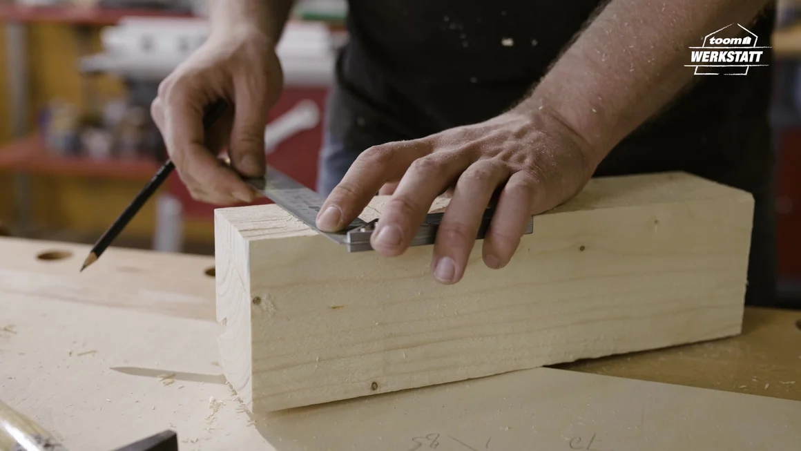 Person misst Holz mit einem Winkel