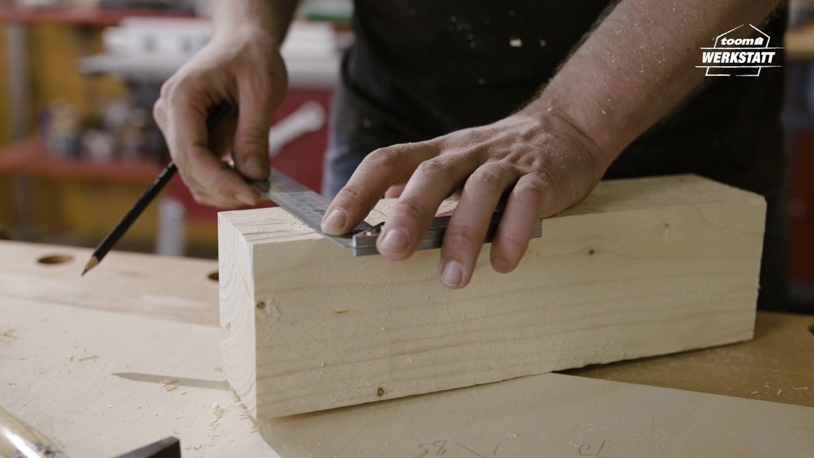 Person misst Holz mit einem Winkel