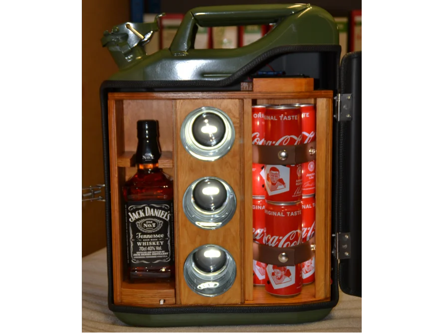 Eine grüne Metallbox mit Holzeinbauten ist geöffnet und zeigt eine Flasche und Dosen im Inneren sowie drei Gläser.