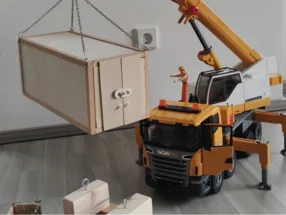 Spielzeugkran hebt Holzkiste