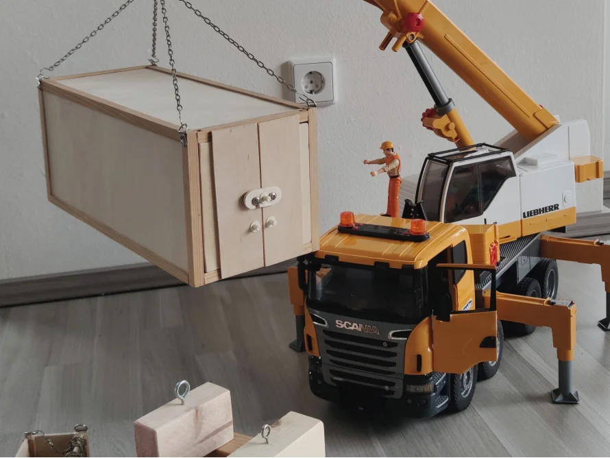 Spielzeugkran hebt Holzkiste