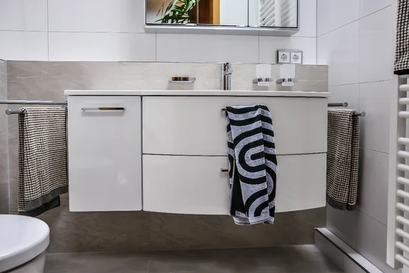 Modernes Badezimmer mit weißem Waschbecken und Handtüchern.