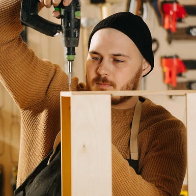 Person verschraubt Holz mit Akkuschrauber