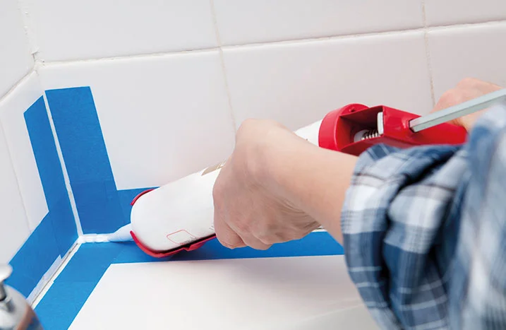 Person versiegelt Fliesen mit Dichtmittel.