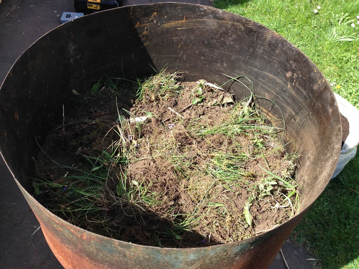 Metallbehälter mit Erde und Gras gefüllt