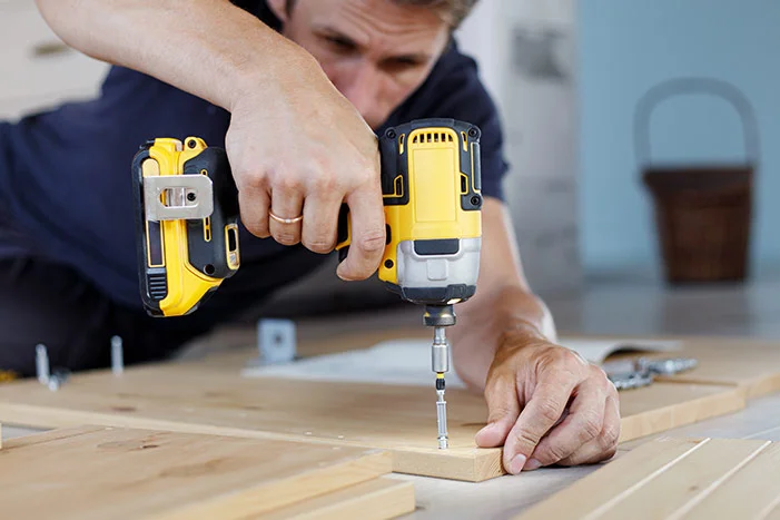 Person verschraubt Holzbretter mit Akkuschrauber