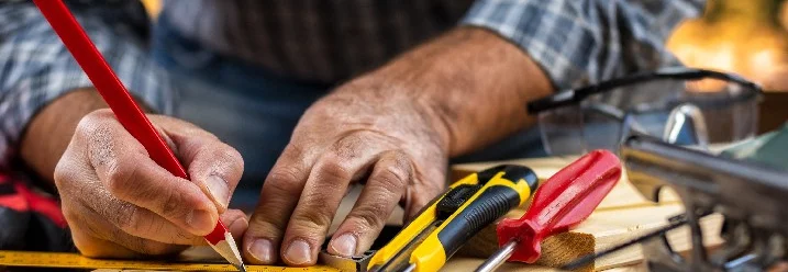 Person zeichnet mit Bleistift auf Holz