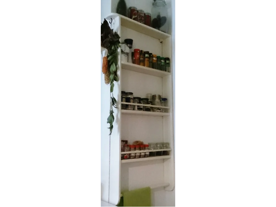 Weißes Gewürzregal mit Gewürzen