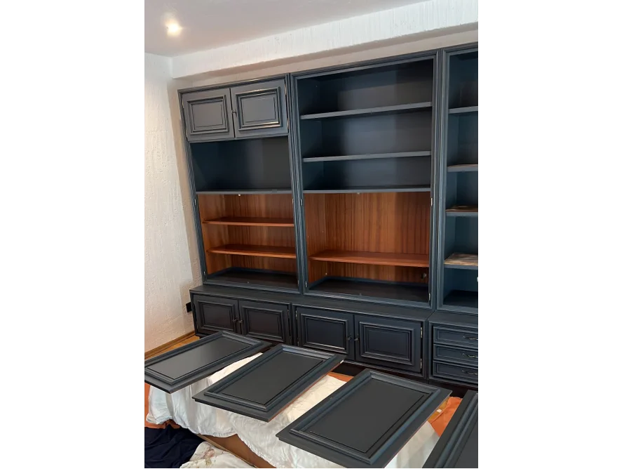 Ein dunkelgraues Bücherregal mit ausgebauten Türen