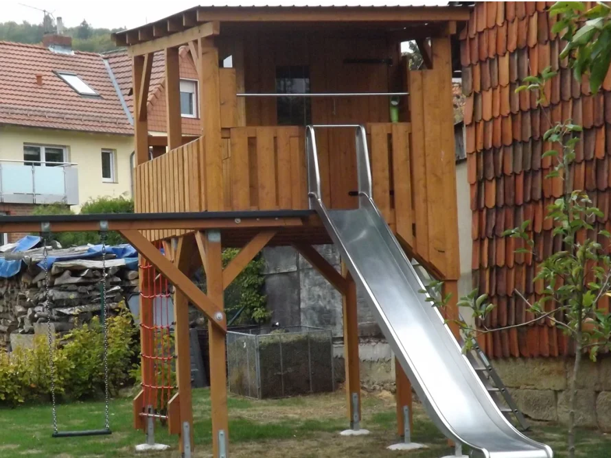 Ein Spielplatz aus Holz mit Rutsche und Schaukel