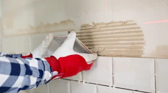 Person bringt Fliese an Wand an