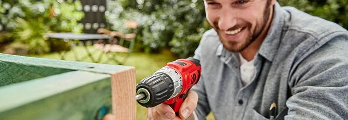 Person baut mit Akkuschrauber Holzkonstruktion