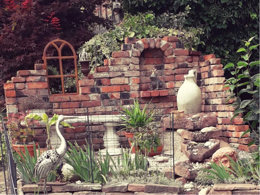 Gartenecke mit Ziegelmauer und Dekoration