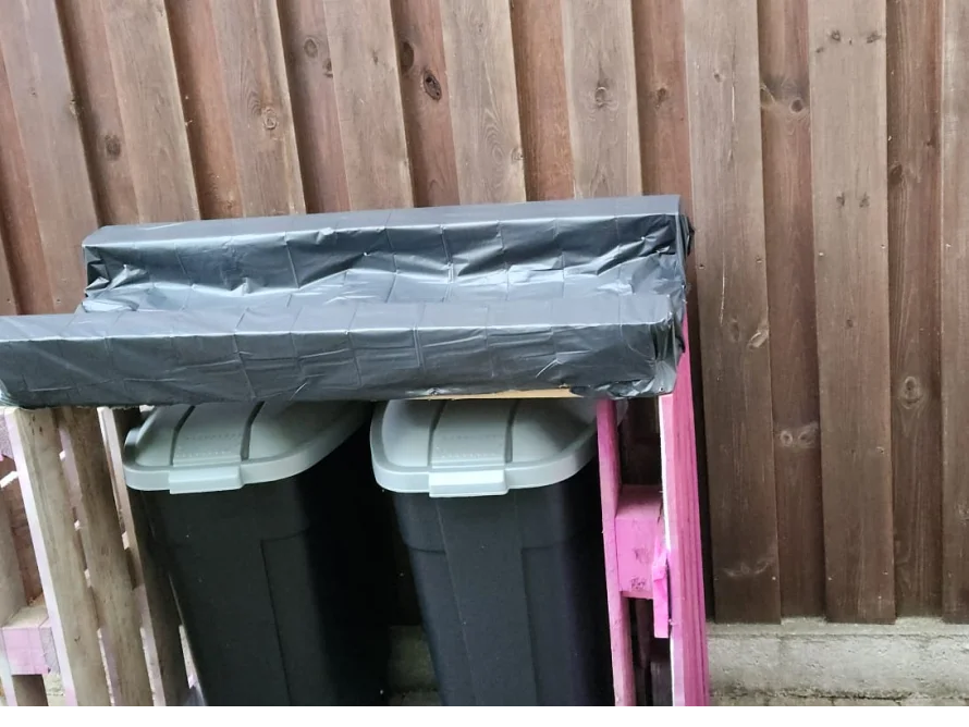 Zwei Mülleimer unter einer Plane