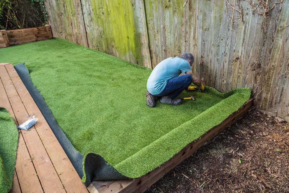 Eine Person verlegt Rasen in einem Garten