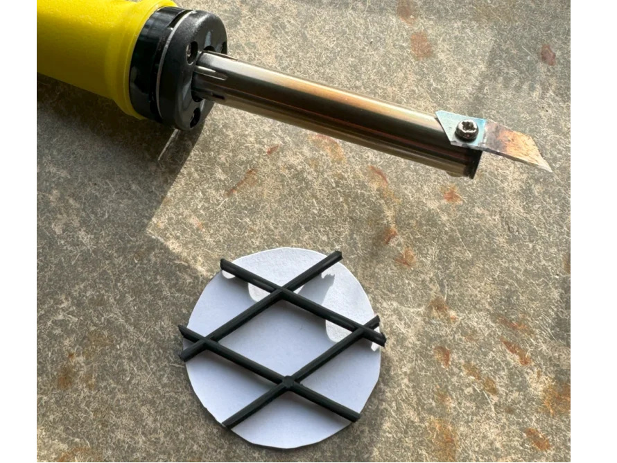 Lötkolben und Plastikgitter auf Tisch