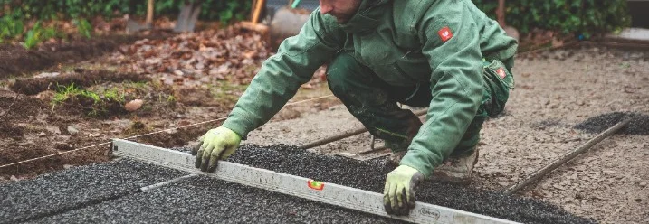 Person ebnet Schotter mit Wasserwaage