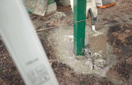 Zaunpfosten setzen Ein Zaunpfosten wird in das Betonfundament gesetzt.