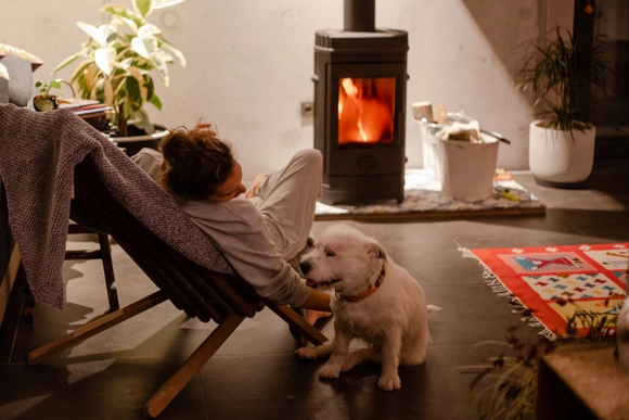 Frau mit Hund vor brennendem Kamin