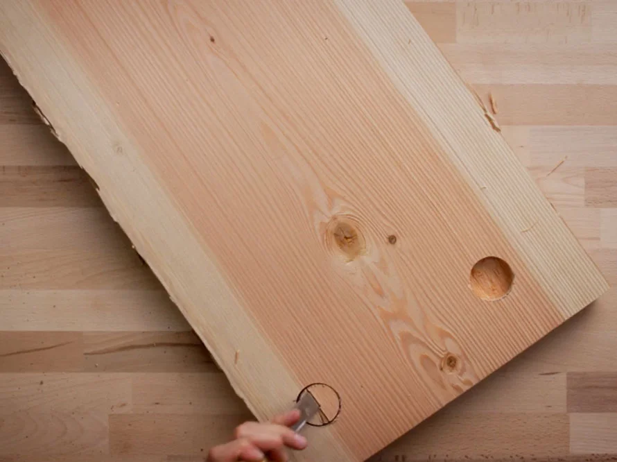 Person schneidet Loch in Holzbrett