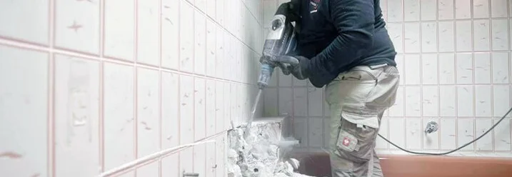 Person entfernt Fliesen mit Bohrhammer
