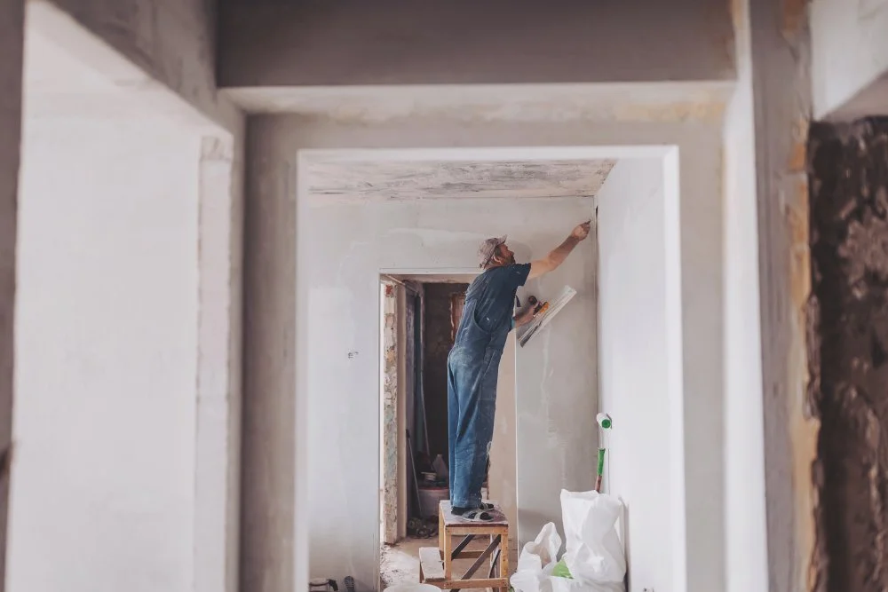 Bauarbeiter auf der Baustelle erneuert Gips von Innenwänden und Decken mit Schwimmer und Gips.