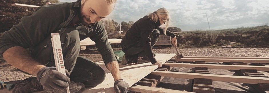Zwei Handwerker bauen eine Holzterrasse.