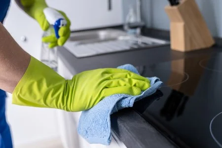 Person reinigt Herd mit Tuch