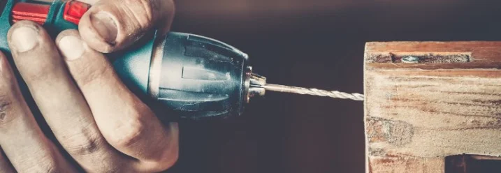 Person verschraubt Holzbalken mit Akkuschrauber