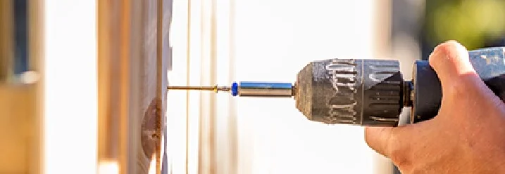 Hand schraubt Holzlatte fest