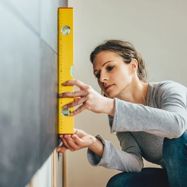 Person richtet Wasserwaage an Wand aus
